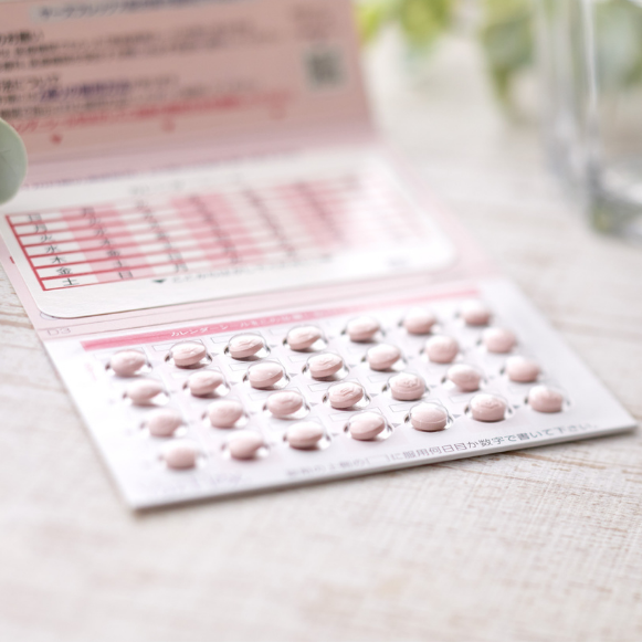 Birth Control Blister pack of birth control pills next to an open calendar pack on a wooden surface