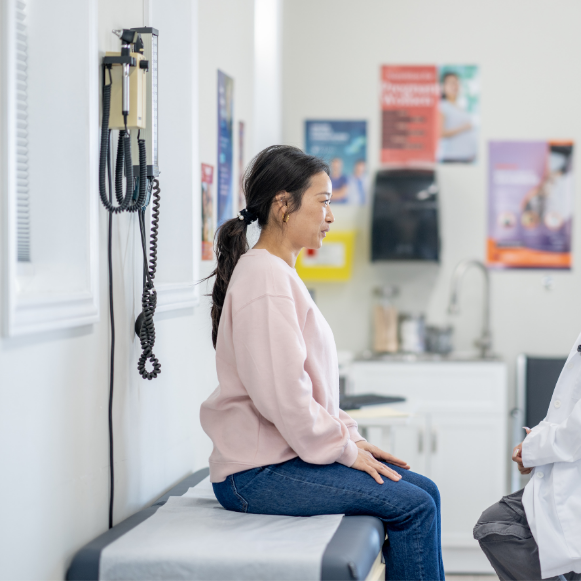 Endometrial Ablation Woman sitting on an exam table in a clinic room, speaking with a provider
