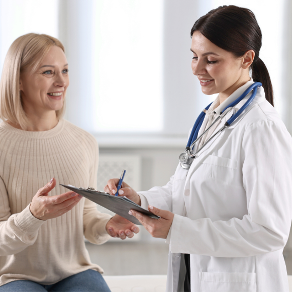Pap Smears Provider in a white coat holding a clipboard while talking with a seated patient