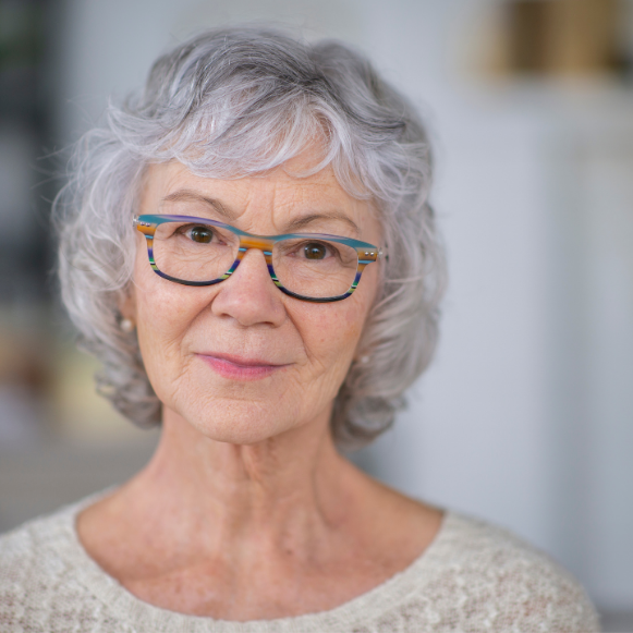 Urinary Incontinence Woman with grey hair and patterned glasses looking at the camera