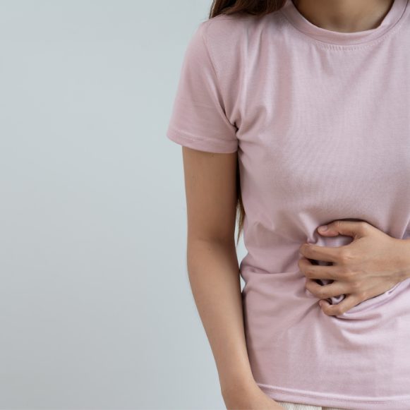 UTI Woman in a pink t-shirt pressing one hand against her lower abdomen